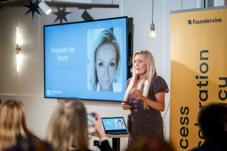A speaker presents beside her slides.