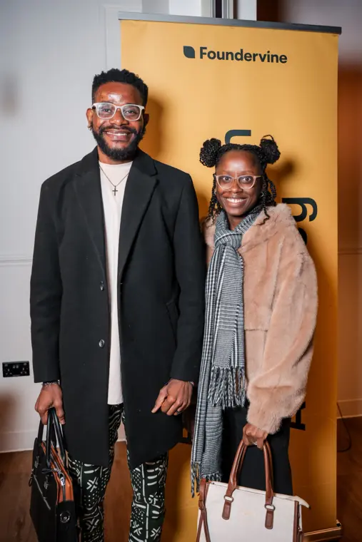 Two attendees pose beside the Foundervine banner.