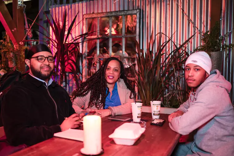 Three attendees share a conversation at a table.