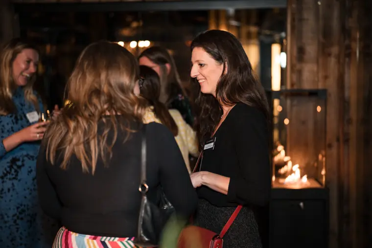 Three guests talk together in the busy room.