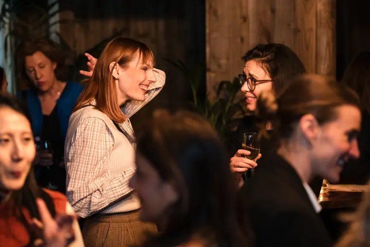 A guest speaks with colleagues near the bar.