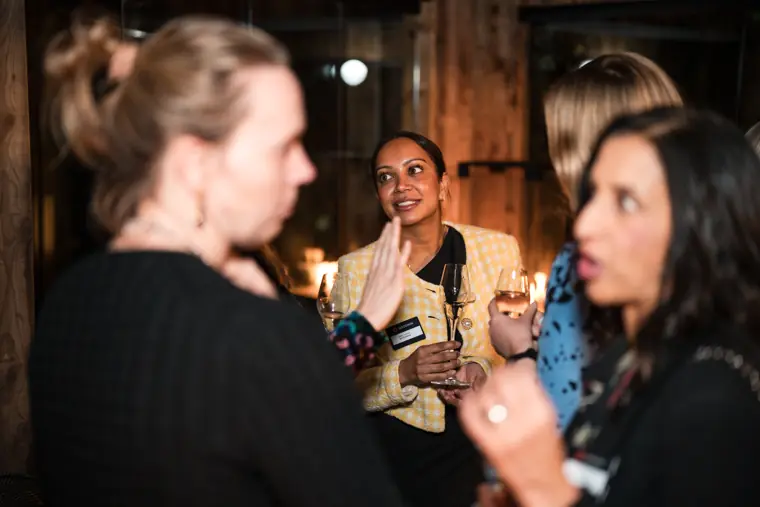 Guests share a conversation in front of the timber wall.