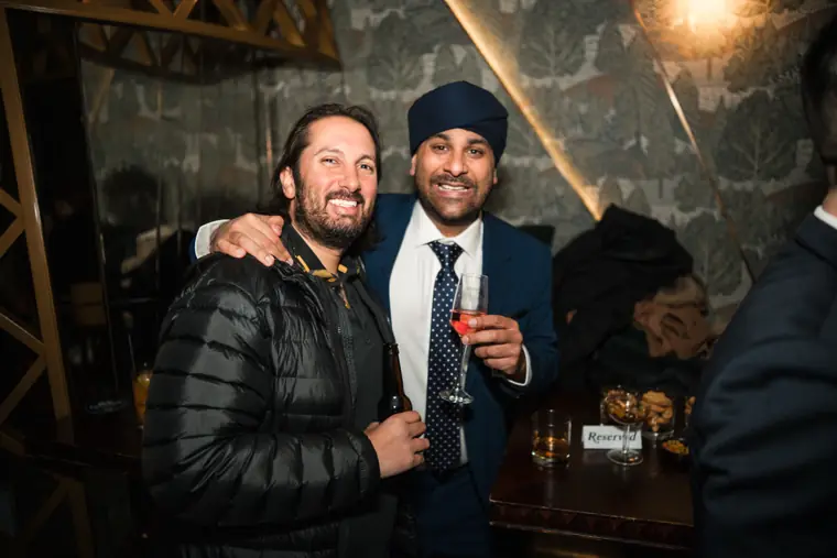 Two guests posing together with drinks at the event.