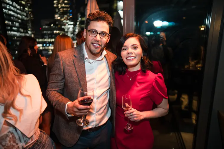A woman in red and a guest talking over drinks.