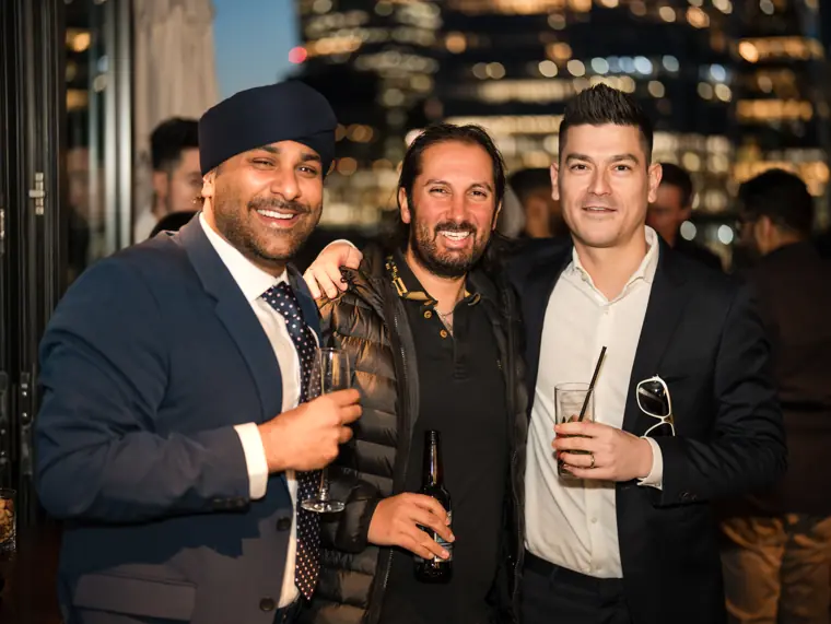 Three colleagues standing together in the evening venue.
