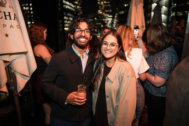 Guests smiling together near the rooftop seating.