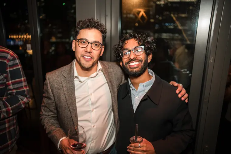 Two attendees posing together in front of the city lights.