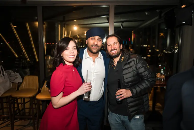 A woman in red posing with two guests.