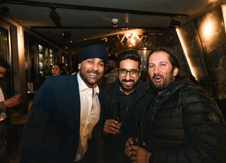 Three guests standing together with drinks.