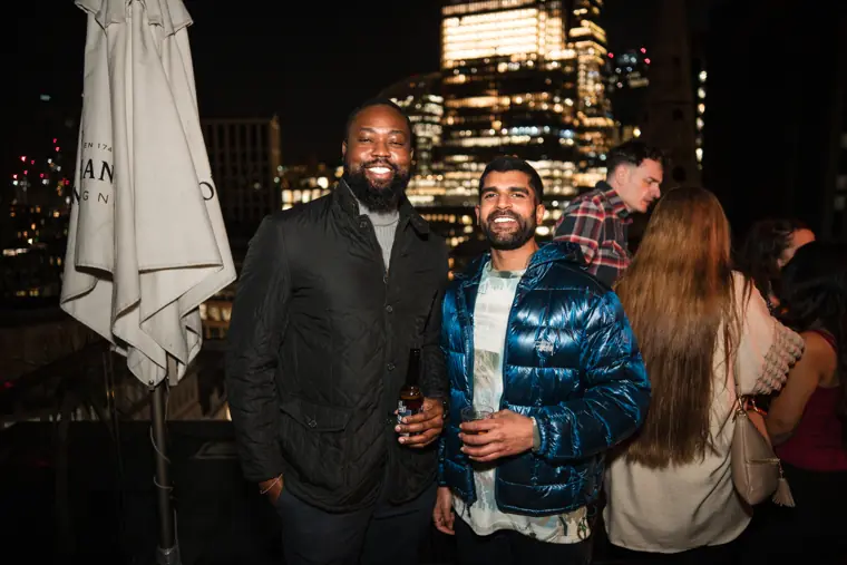 Two guests talking beside the illuminated rooftop.