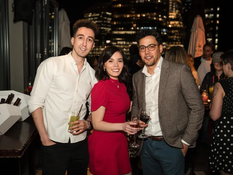 Three guests smiling together during the evening.