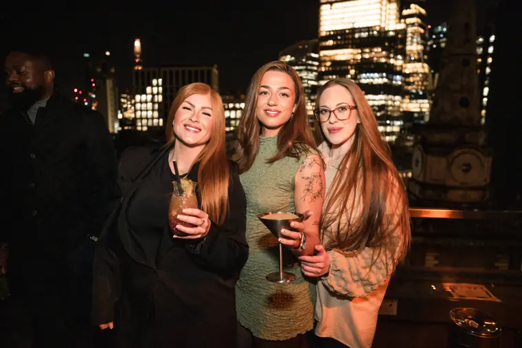 Three women talking together with drinks.