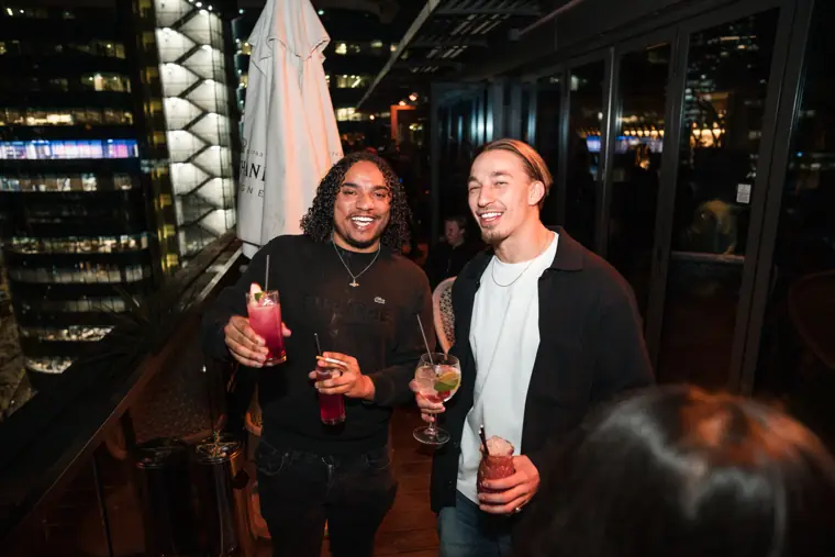 Two guests smiling together beside the rooftop windows.