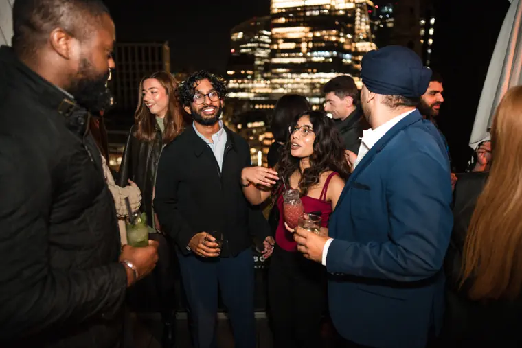 A group of men talking over drinks at night.