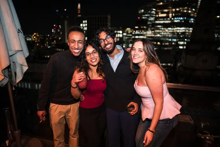 Friends smiling together in a rooftop group portrait.