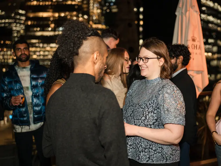 Two guests talking by the rooftop railing.