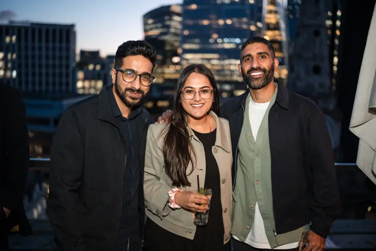 Three guests posing together with the city behind them.