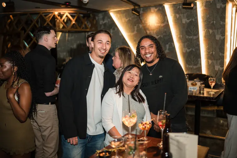 Four guests posing together beside the drinks table.