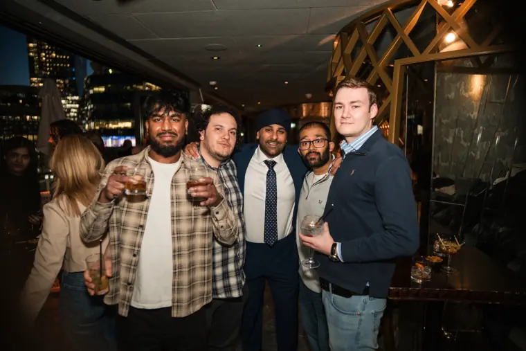 Four men standing together at the rooftop gathering.
