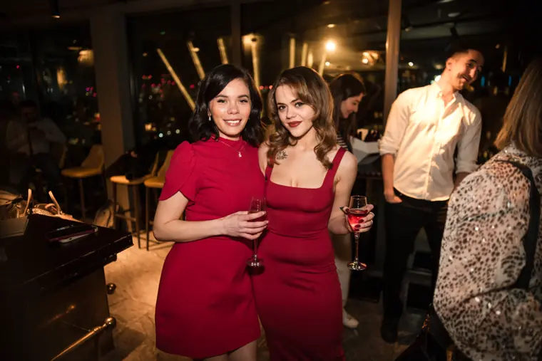 Two women in red dresses posing together at the event.