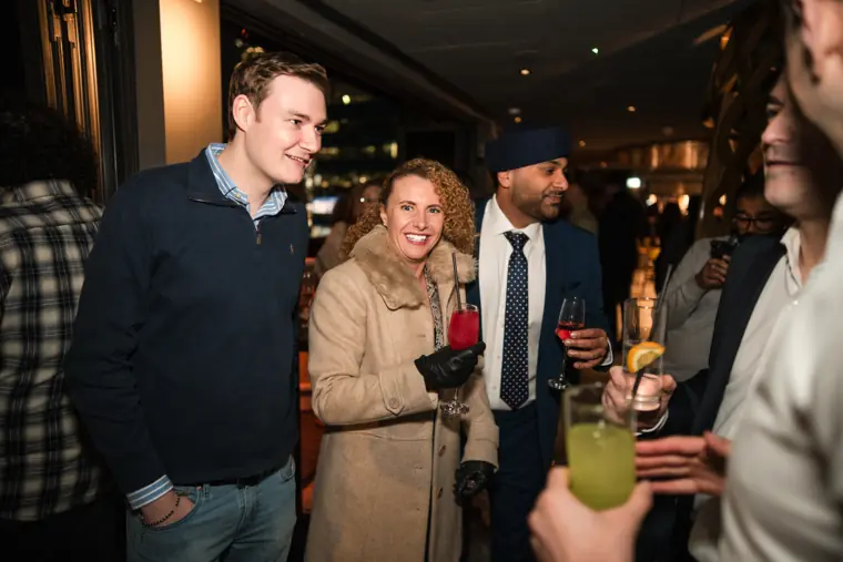 Three guests posing together with drinks.