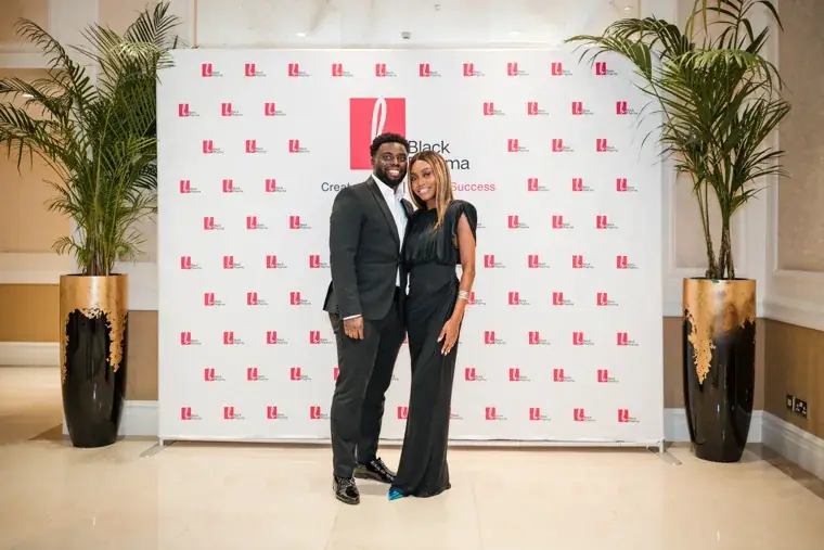 Couple posing together against the Black Pharma backdrop at the Black Pharma fifth anniversary gala.