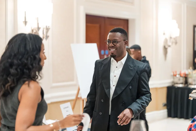 Guest greeting an arriving attendee in the foyer at the Black Pharma fifth anniversary gala.
