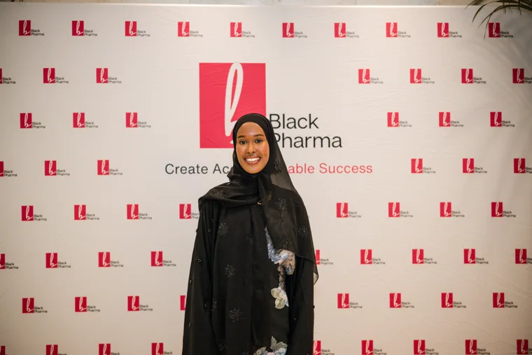 Guest wearing a headscarf posing at the gala photo wall at the Black Pharma fifth anniversary gala.