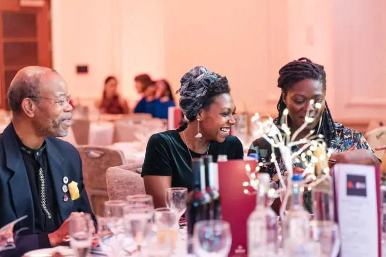 Guests smiling and talking across their dinner table at the Black Pharma fifth anniversary gala.