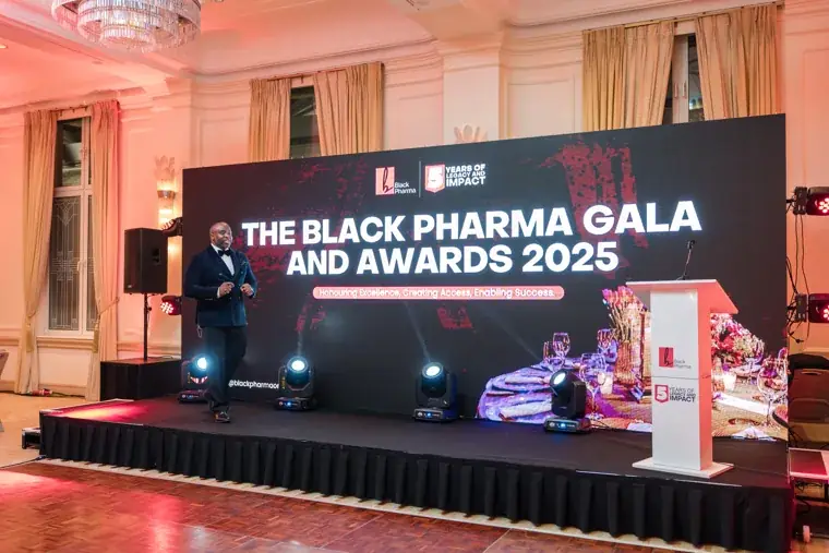 Host walking onto the Black Pharma gala stage at the Black Pharma fifth anniversary gala.