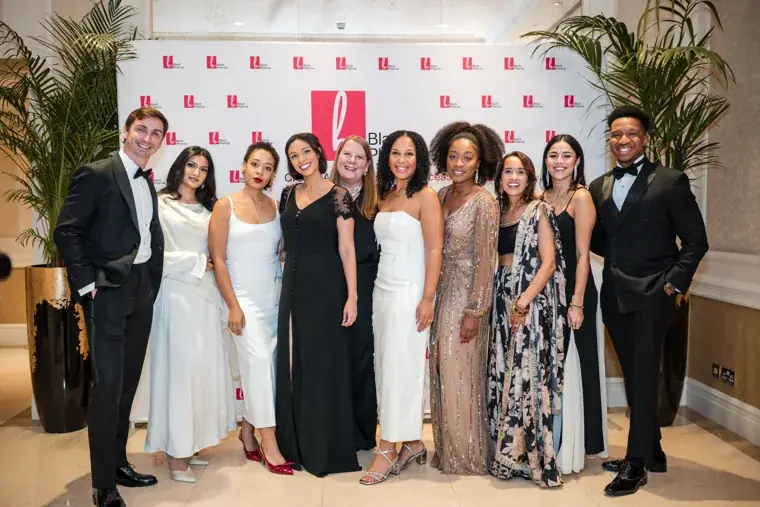 Large group of gala guests posing against the photo wall at the Black Pharma fifth anniversary gala.