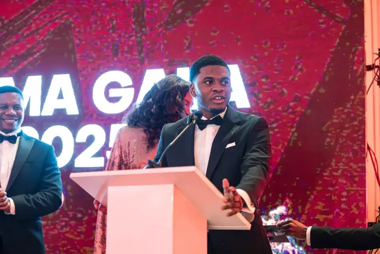 Presenter speaking into a microphone on the gala stage at the Black Pharma fifth anniversary gala.