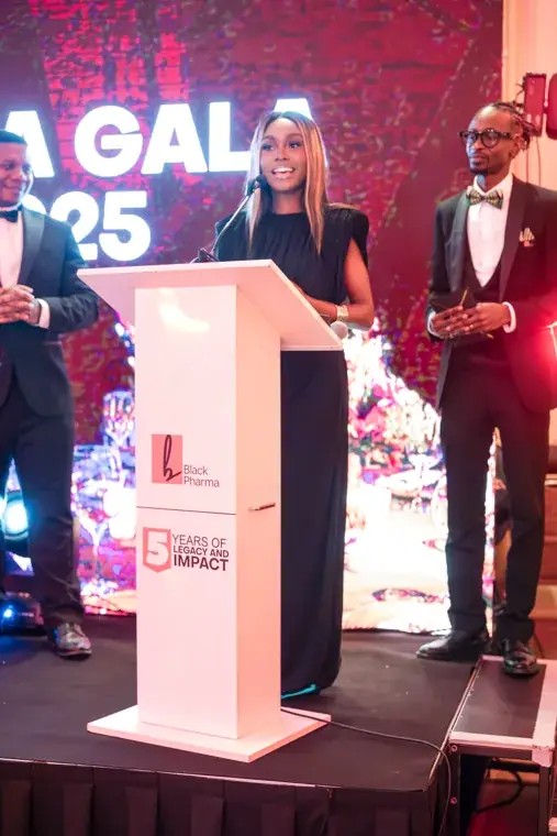 Presenter speaking while a co-presenter stands beside the lectern at the Black Pharma fifth anniversary gala.