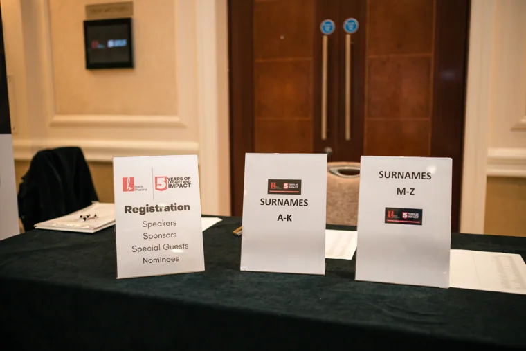 Registration signs arranged on the welcome table at the Black Pharma fifth anniversary gala.