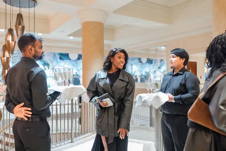 Small group networking beside the foyer staircase at the Black Pharma fifth anniversary gala.