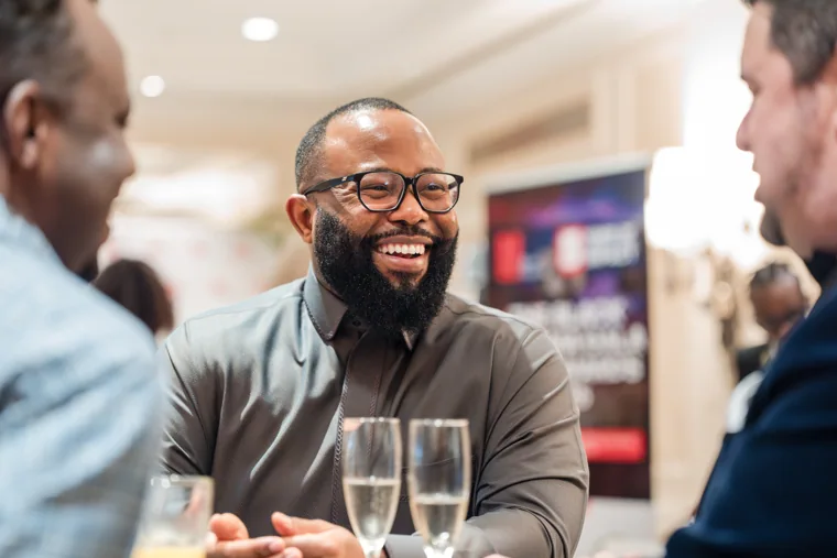 Smiling guest listening during a lively conversation at the Black Pharma fifth anniversary gala.