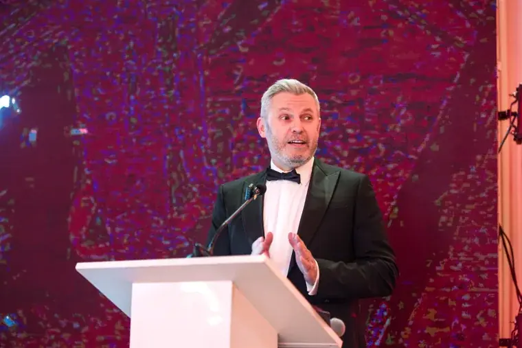 Speaker in a tuxedo addressing guests from the lectern at the Black Pharma fifth anniversary gala.