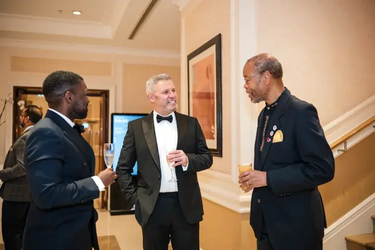 Three guests networking near the ballroom entrance at the Black Pharma fifth anniversary gala.