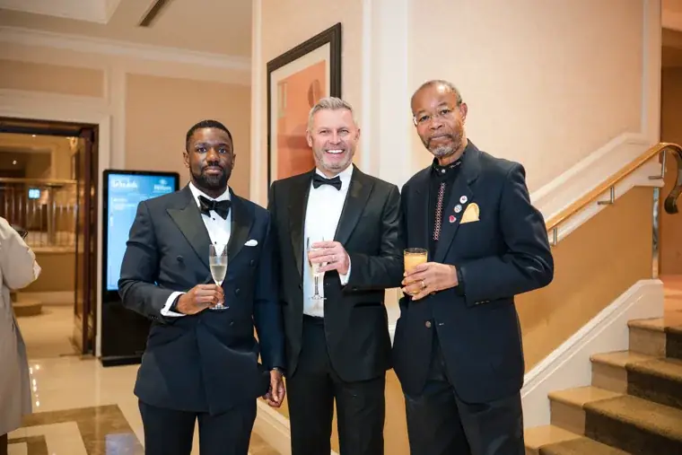 Three guests smiling together with drinks in hand at the Black Pharma fifth anniversary gala.