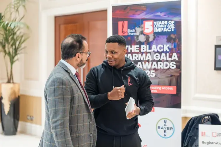 Two guests in conversation beside the gala welcome sign at the Black Pharma fifth anniversary gala.