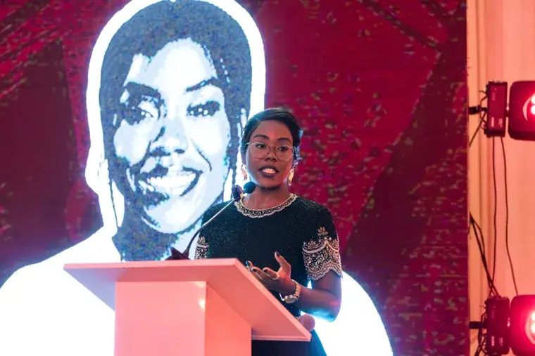 Woman speaking beneath a projected award portrait at the Black Pharma fifth anniversary gala.