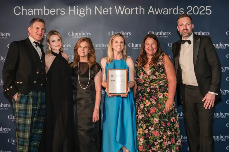 A group celebrating with a trophy at the Chambers photo wall at the Chambers High Net Worth Awards 2025.