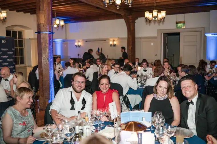 A group of guests posing at a table beneath the timber beams at the Chambers High Net Worth Awards 2025.