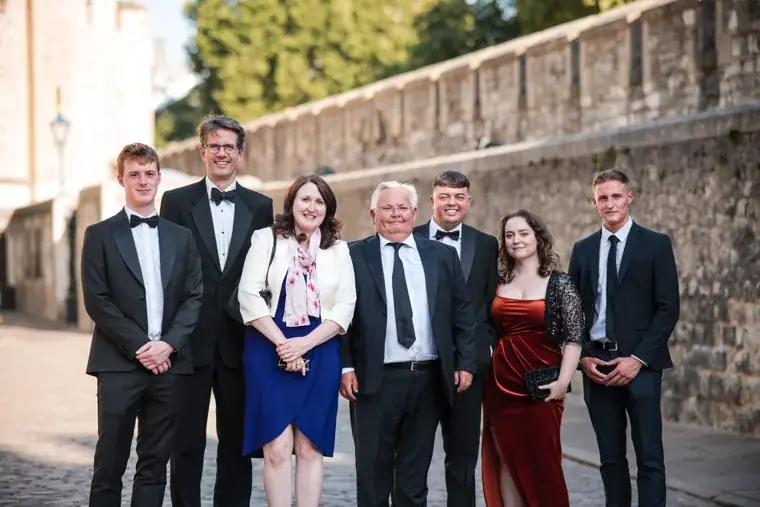 A group of seven guests posing beside the Tower wall at the Chambers High Net Worth Awards 2025.