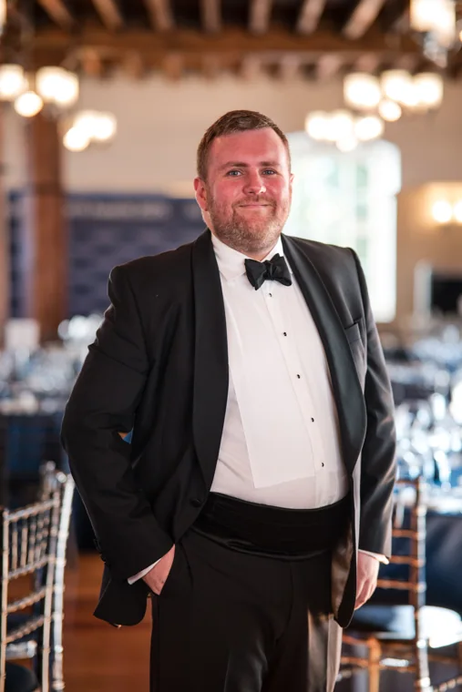 A guest in black tie standing inside the timber-beamed dining room at the Chambers High Net Worth Awards 2025.