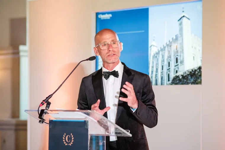 A speaker addressing the room with the Tower image projected behind him at the Chambers High Net Worth Awards 2025.