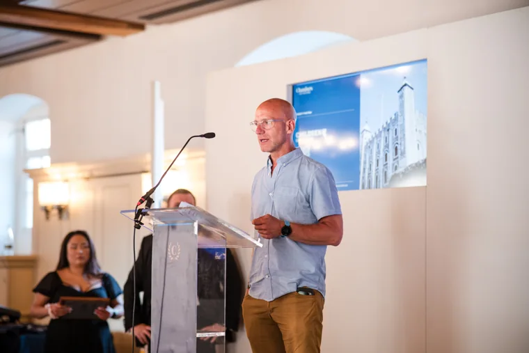 A speaker holding notes beside the presentation lectern at the Chambers High Net Worth Awards 2025.