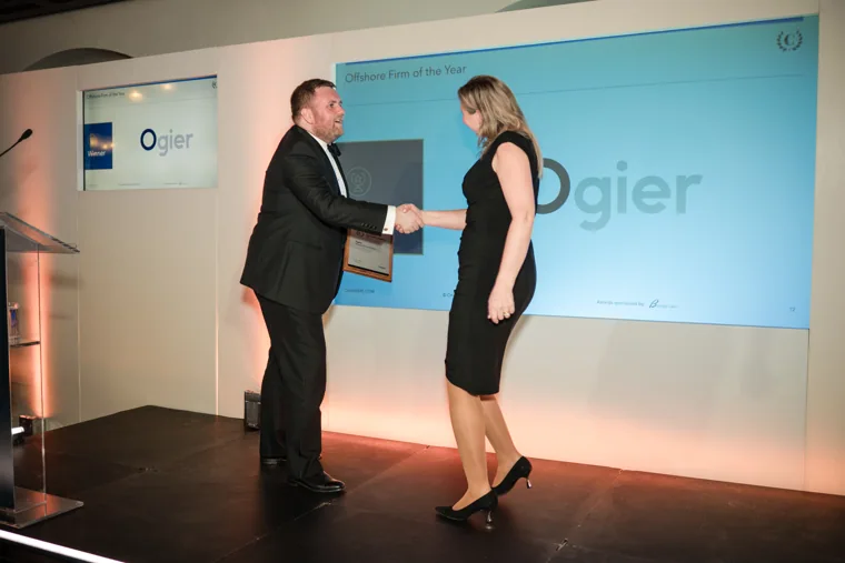 An award recipient shaking hands with the presenter on stage at the Chambers High Net Worth Awards 2025.