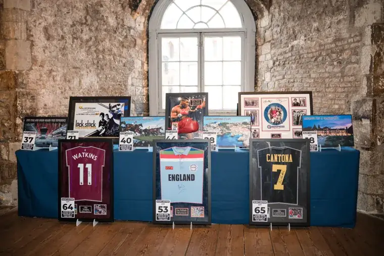 Framed artwork and signed sports shirts displayed during the event at the Chambers High Net Worth Awards 2025.