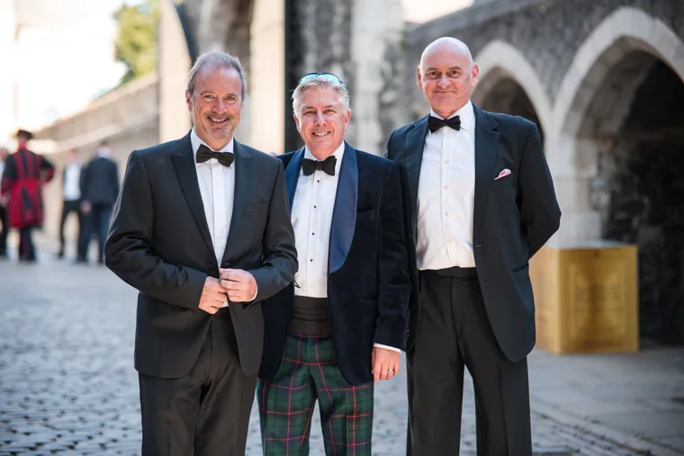 Three guests in dinner jackets posing together near the gateway at the Chambers High Net Worth Awards 2025.